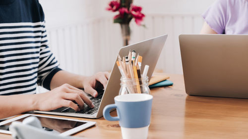 Midsection of man using laptop on table