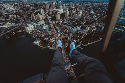 Low section of man sitting in helicopter over buildings in city