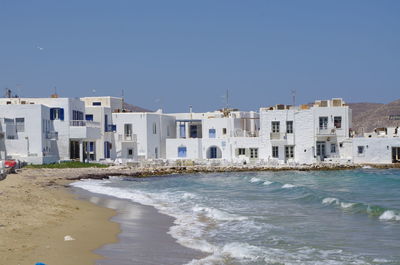 Houses by sea against clear sky