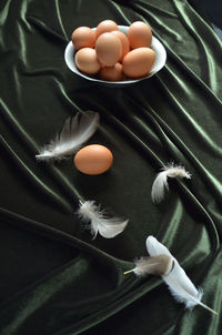 High angle view of brown eggs and feathers on fabric