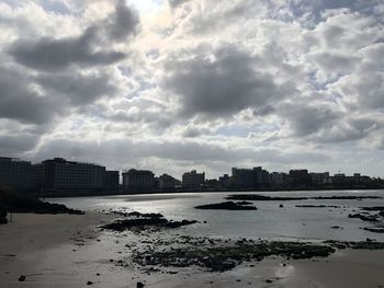 Scenic view of river by buildings against sky