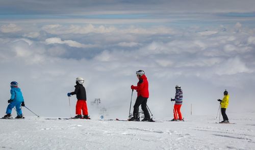 People skiing on snowcapped mountain against sky