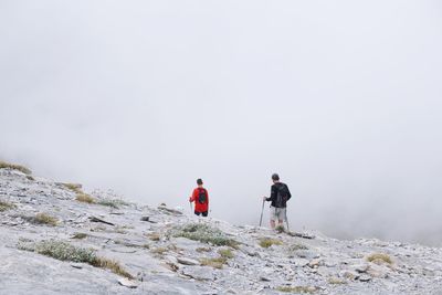 People on snowcapped mountain against sky during winter
