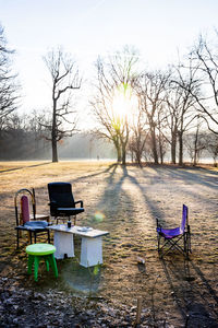 Empty chairs and table on field against sky