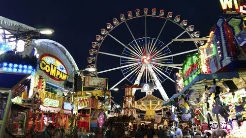 Illuminated ferris wheel against sky at night