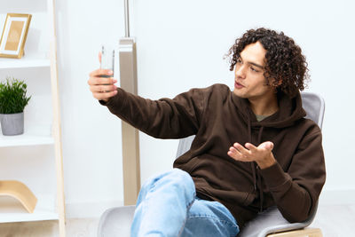 Portrait of young woman using mobile phone while sitting on sofa at home