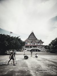 Photographers standing with cameras in front on temple against sky