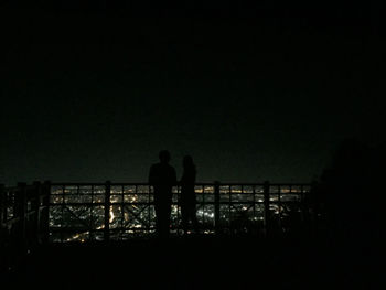 Silhouette man standing by railing against clear sky at night