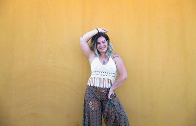 Portrait of a smiling young woman dancing flamenco dance against yellow wall