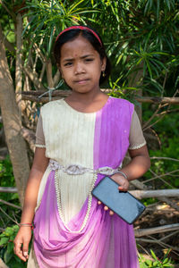 Portrait of young woman standing against plants