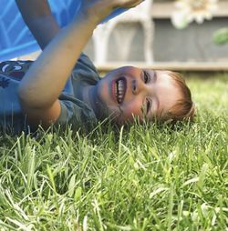 Portrait of boy laying in the grass laughing