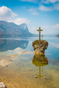 Cross on lake against sky