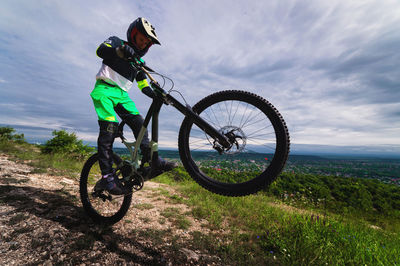 Low angle view of man riding bicycle on field