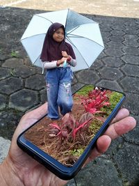 Woman holding umbrella while standing on street during rainy season