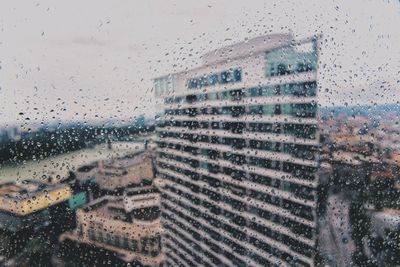 Buildings seen through wet glass window during rainy season