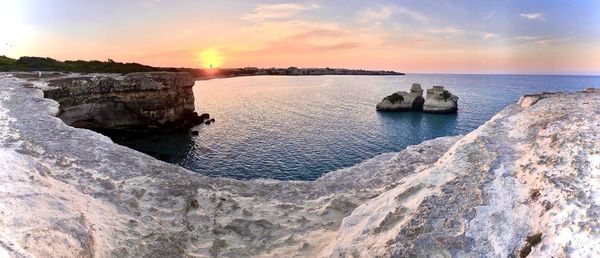 Rocks in sea against sky during sunset