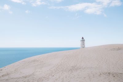 Lighthouse on beach against sky