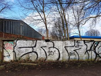 Bare trees by wall against building