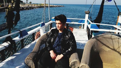 Portrait of young man sitting on boat sailing in sea