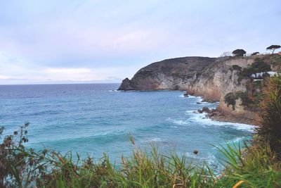 Scenic view of sea by cliff against sky