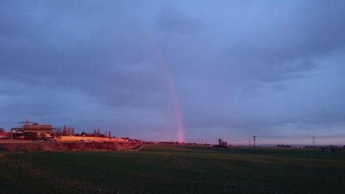 Scenic view of rainbow over field against sky