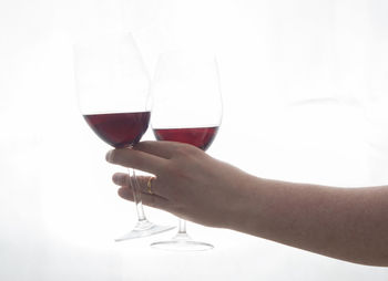 Close-up of hand holding drink against white background