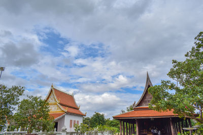 Low angle view of trees and building against sky