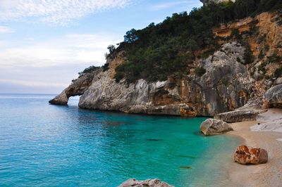 Scenic view of rocks by sea against sky