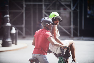 Man cycling while woman sitting on bicycle basket in city