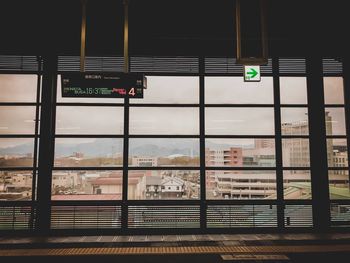 Information sign on glass window against buildings in city