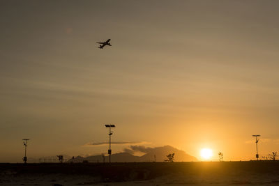 Low angle view of silhouette airplane against sky during sunset