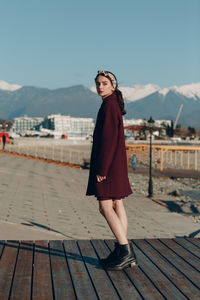 Portrait of young woman standing on mountain against sky