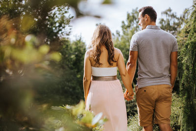 Rear view of couple holding hands while walking at park