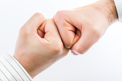 Close-up of man holding hands over white background
