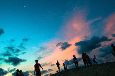 Silhouette people walking against sky during sunset