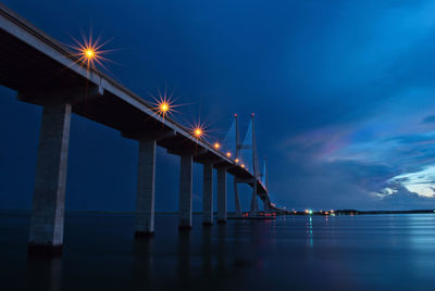 Illuminated sidney lanier bridge over brunswick river against cloudy sky