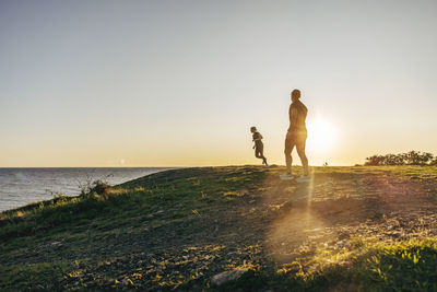 Women exercising on hill near sea at sunset