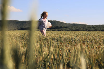 Rear view of woman standing on field against clear sky