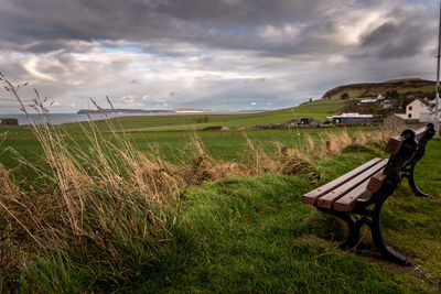 Lonely bench in a cold and windy coastal city, pointing to the sea with dramatic cloudy sky