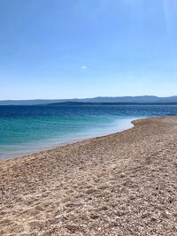 Scenic view of beach against clear blue sky