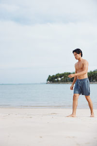 Full length of boy standing at beach against sky