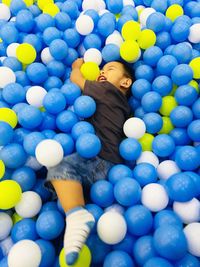 Cute boy playing with balls in pool