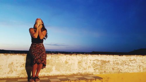 Thoughtful woman looking up against sky at dusk