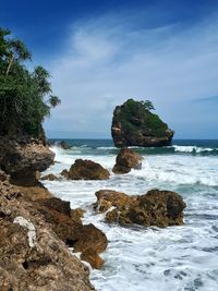 Scenic view of rocks on beach against sky