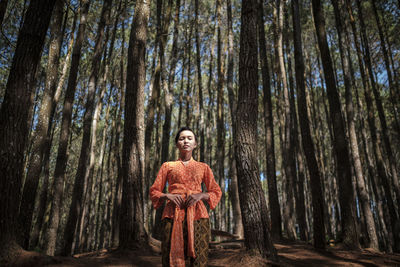 Portrait of woman standing against trees in forest