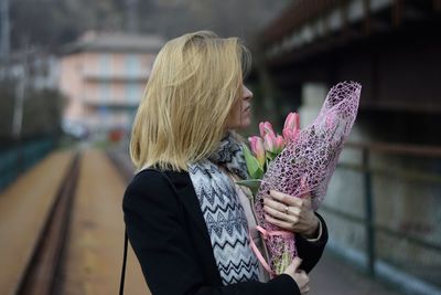 Midsection of woman holding pink umbrella standing at dusk