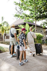 Smiling girl with mother and father arriving at tourist resort during vacation