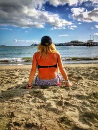 Rear view of woman on beach against sky