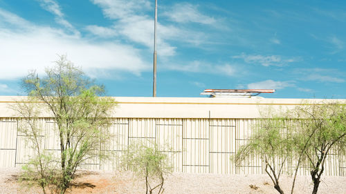 Plants by building against sky on sunny day
