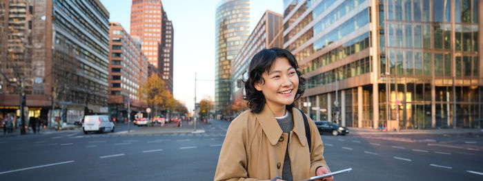 Portrait of young woman standing in city